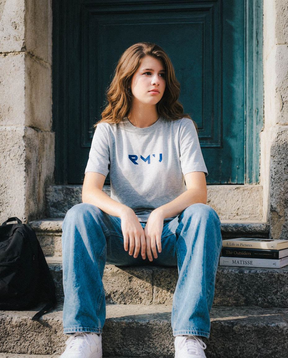 Laura con camiseta Core gris jaspeado y logotipo RMU azul, sentada en unas escaleras