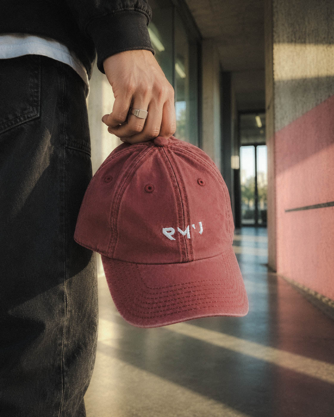 Gorra Core burdeos llevada en la mano en un pasillo