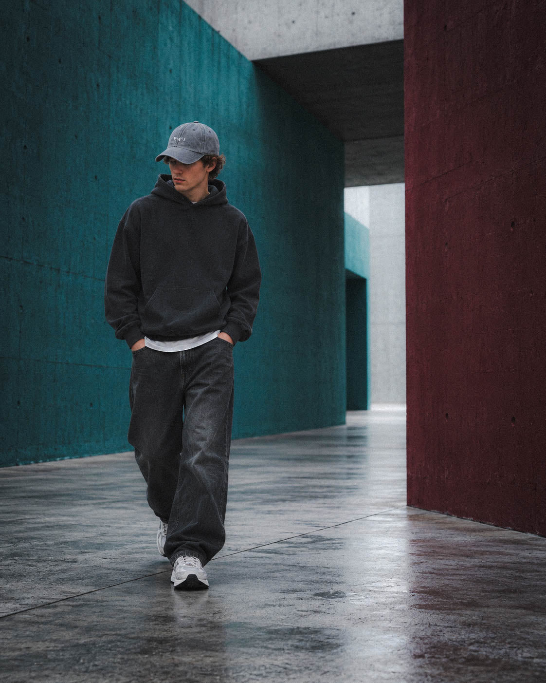 Chico con gorra Core gris oscuro caminando entre muros azules y granates