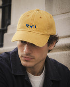 Chico con gorra Core mostaza en unas escaleras