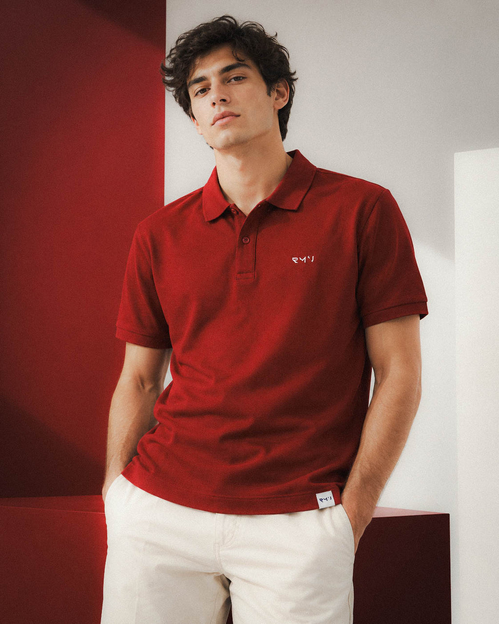 Chico con polo Core burdeos y pantalón blanco en una composición de paneles
