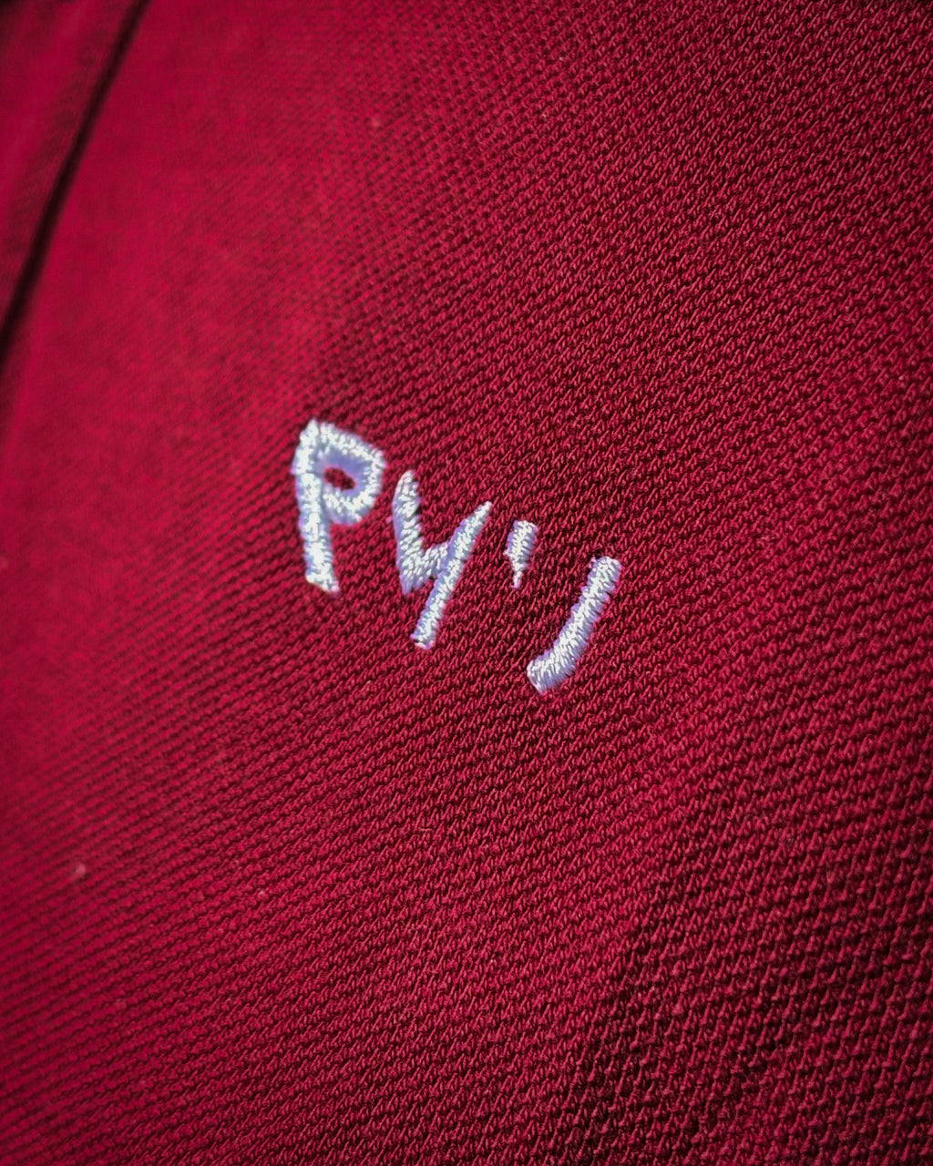 Detalle del bordado blanco RMU y del tejido piqué del polo Core burdeos