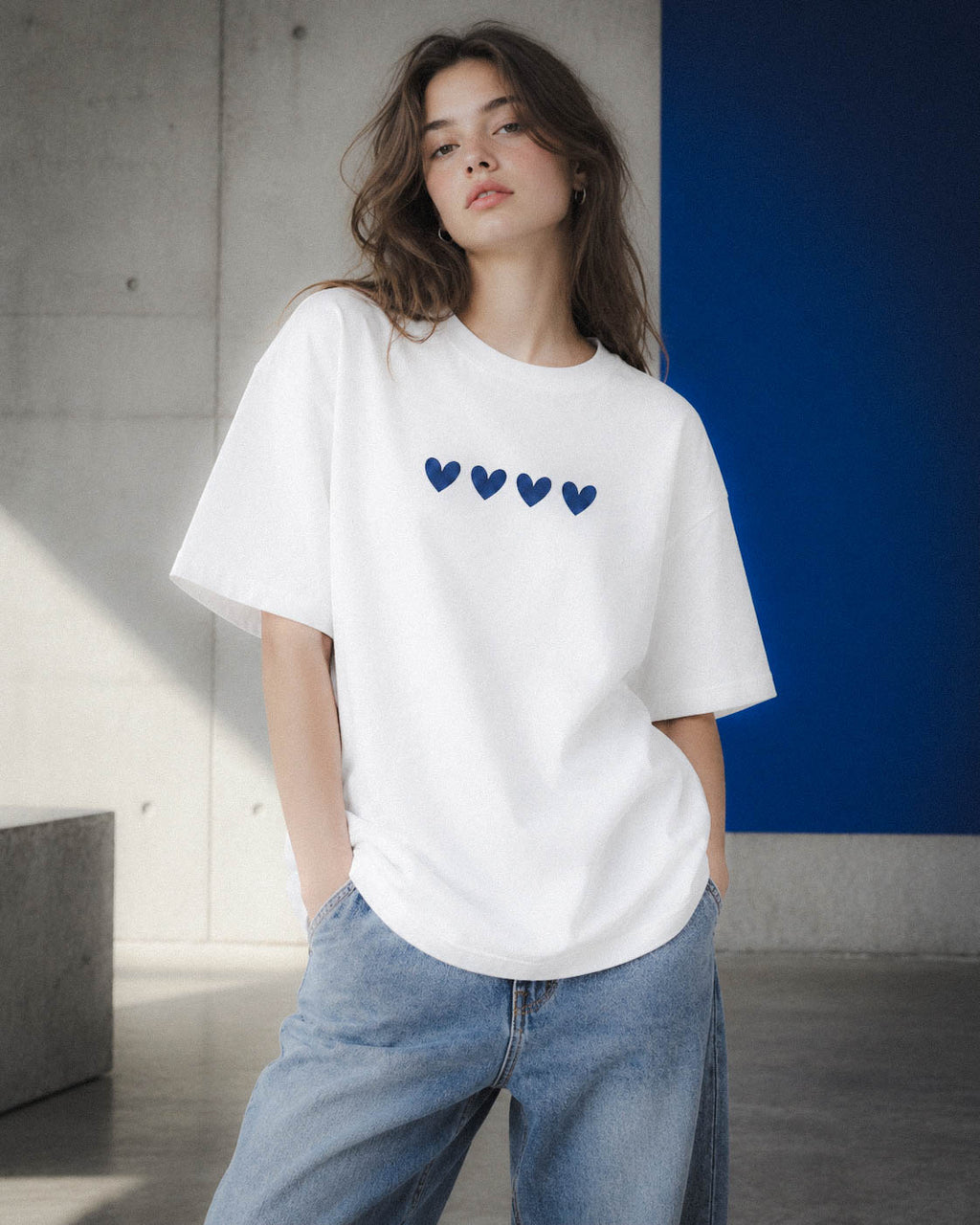 Chica con camiseta Four Hearts junto a un panel azul