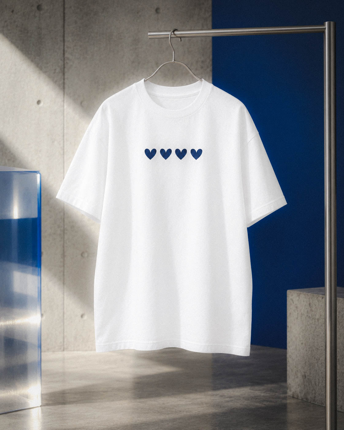 Camiseta Four Hearts suspendida junto a una escalera y un panel azul