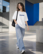 Chica con camiseta Four Hearts y bolso negro caminando junto a unas escaleras