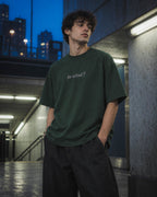 Chico con camiseta So What verde en unas escaleras al anochecer