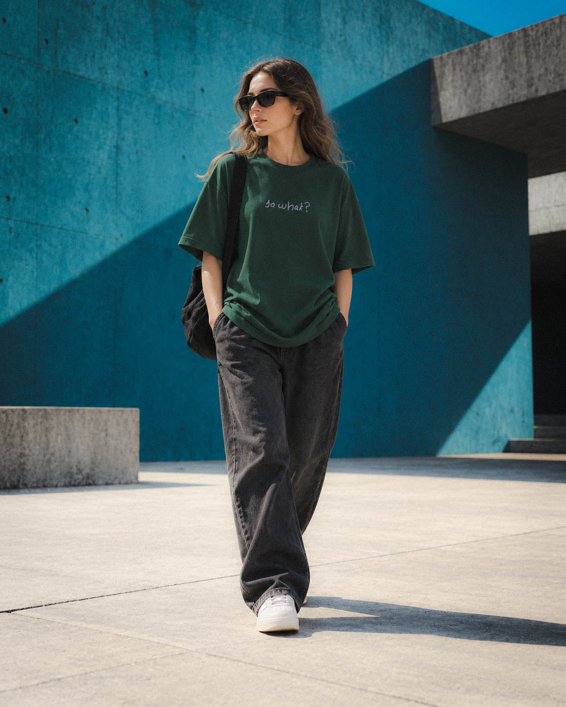 Chica con camiseta So What verde caminando junto a una pared azul